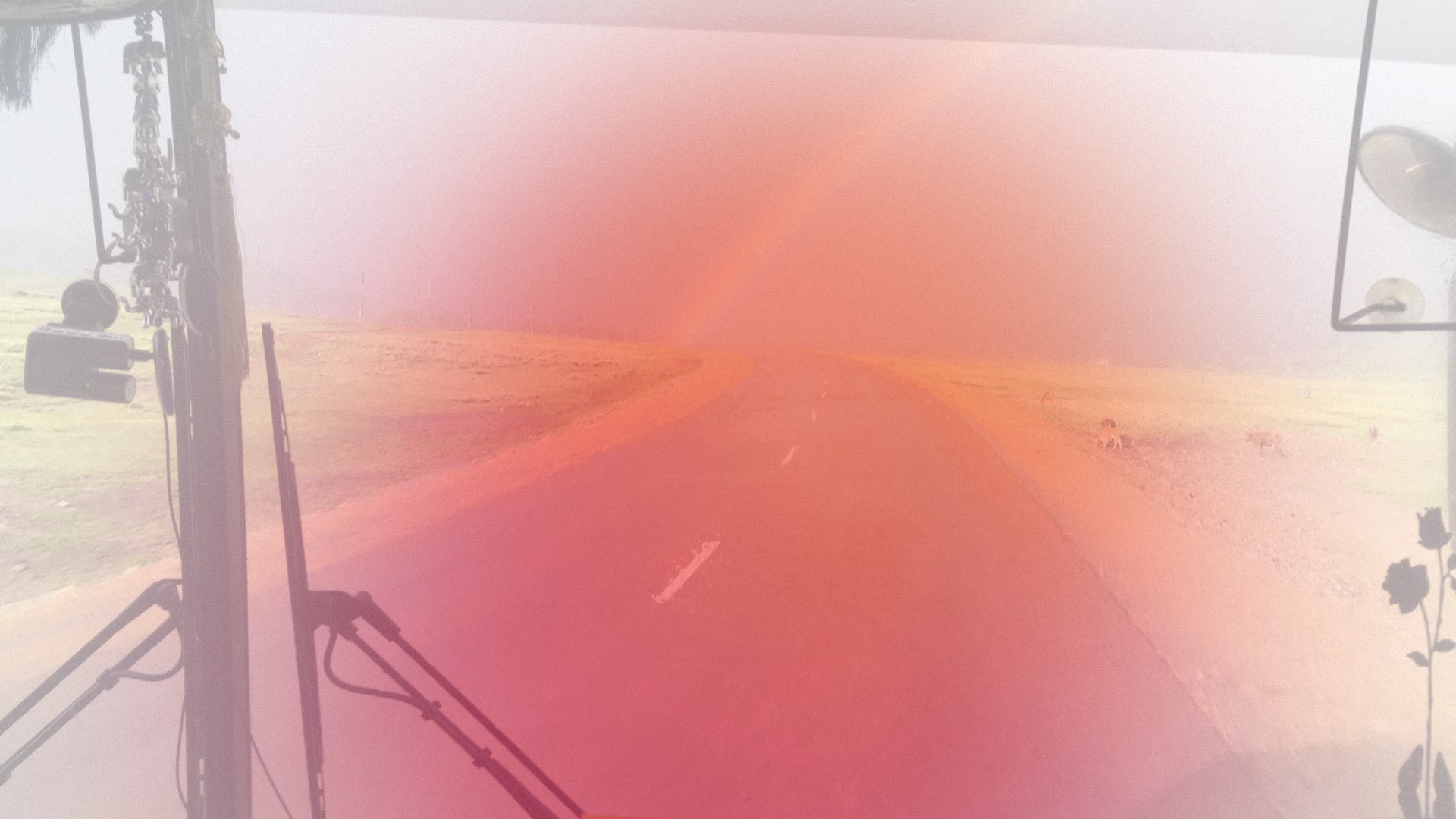 Foto vom Blick aus dem Busfenster in weite mongolische Landschaft mit Regenbogen